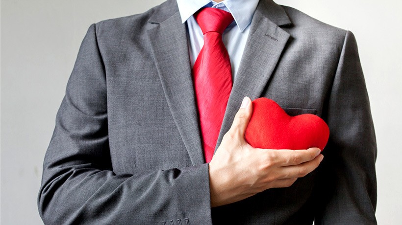 A professional in a suit holding a red heart, symbolising customer care