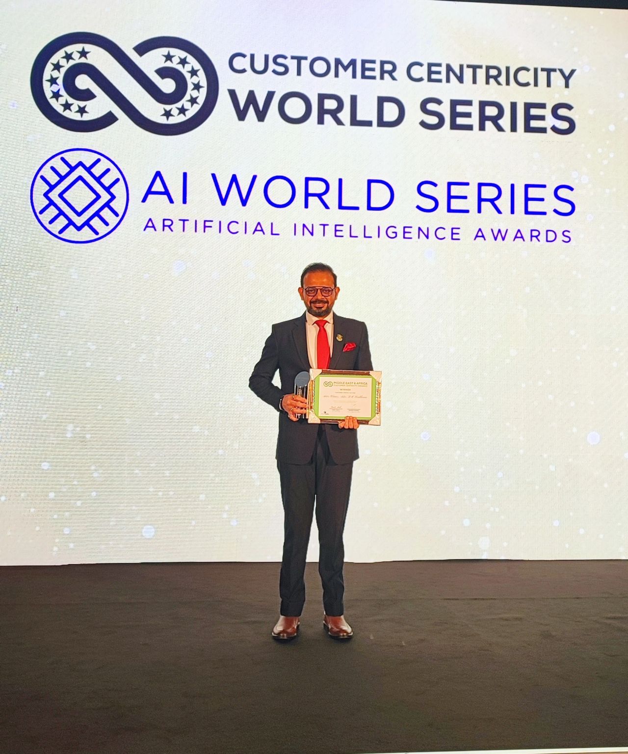 MAGICX founder Pradeep Kumar on stage holding a winner certificate and trophy at the Customer Centricity World Series