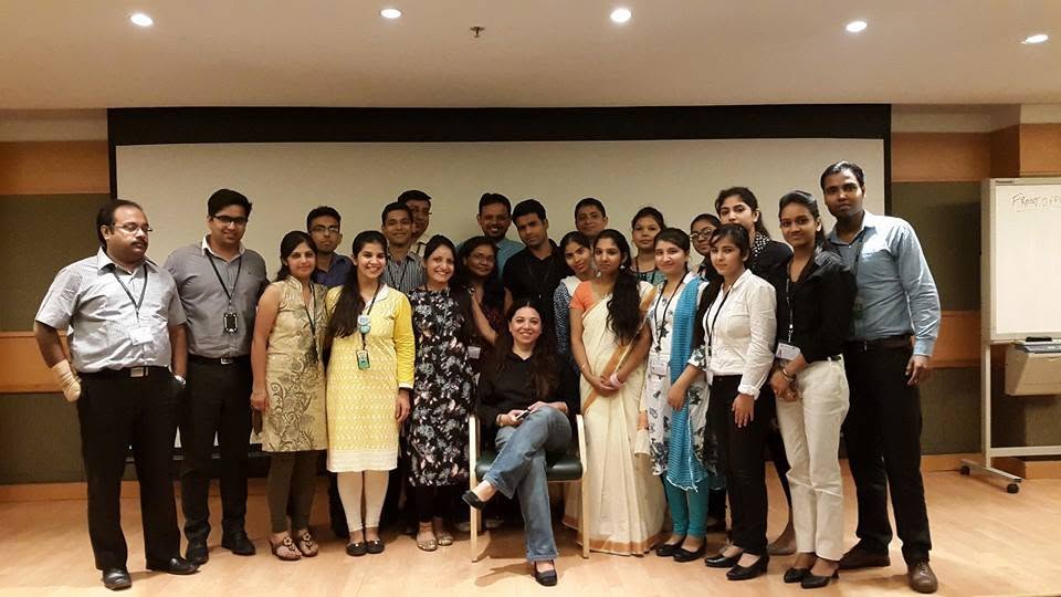 A training batch of around twenty learners standing together at the front of a classroom