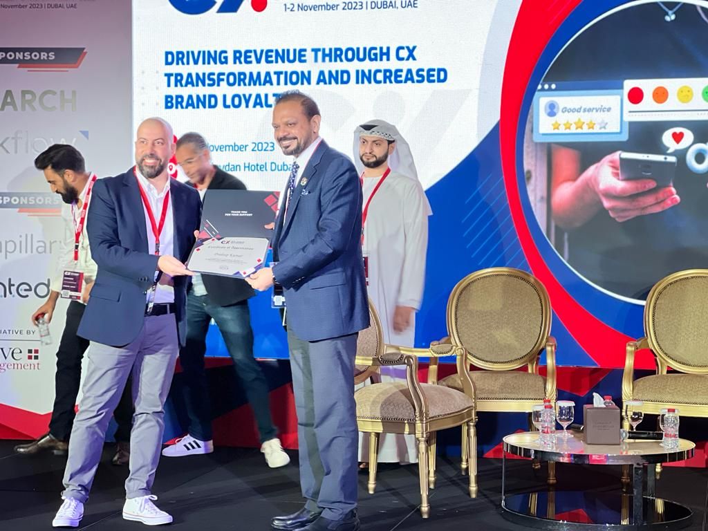 A certificate being presented on stage at the CX and Loyalty Summit and Awards MENA 2023
