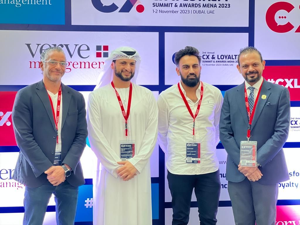 Four speakers standing in front of the CX and Loyalty Summit and Awards MENA 2023 backdrop