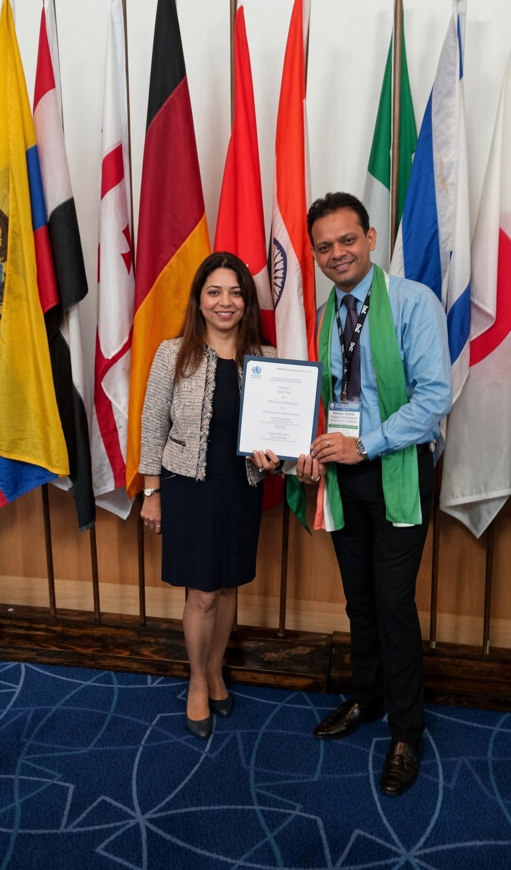 Two professionals holding a certificate of recognition in front of a row of international flags