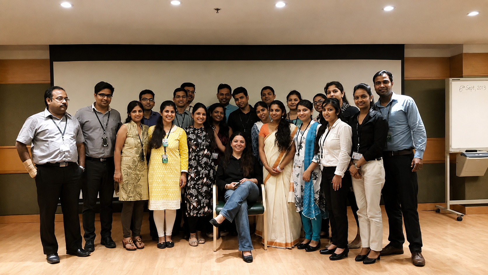 A large training batch of about twenty-four learners posing together in a training room