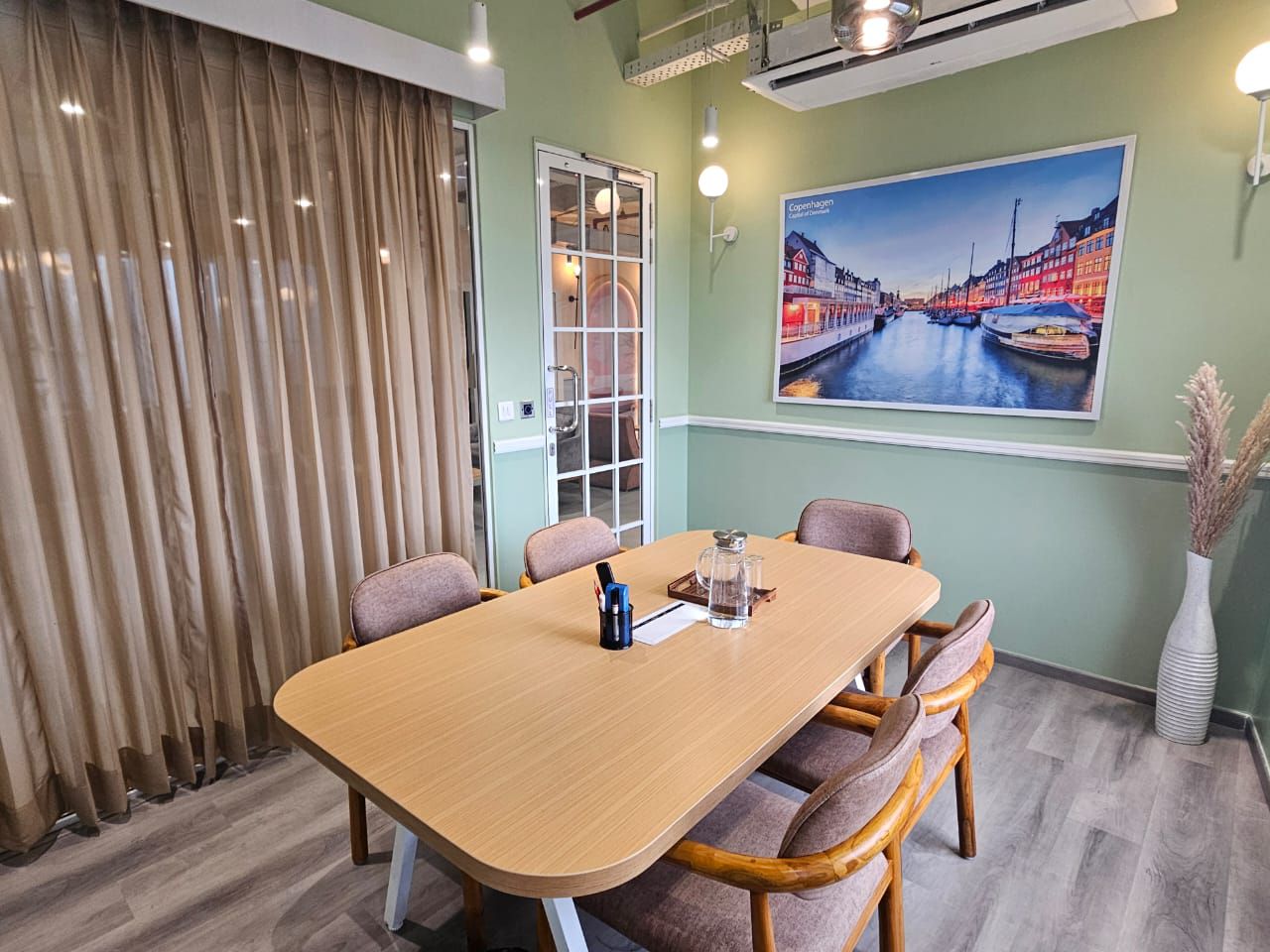 MAGICX meeting room with a conference table, wall-mounted screen and city artwork